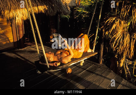 Mexiko. Halbinsel Yucatan. Tulum. Frau auf der Couch entspannen, Buch zu lesen. Stockfoto