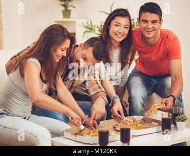 Vier Fröhlichen Freunden heraus hängen in einer Wohnung. Sie haben Spaß und essen Pizza. Selektive konzentrieren. Stockfoto