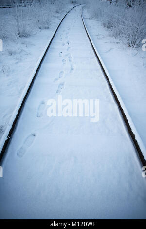 Eisenbahnschienen im Winter mit Fuß auf Schnee vorwärts führenden Stockfoto