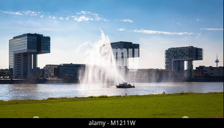 Deutschland, Köln, Feuerlöschboot duiring eine Löschübung am Rhein, Kran Häuser in Rheinau Hafen. Deutschland, Koeln, Feuerloeschboot bei Stockfoto