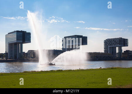 Deutschland, Köln, Feuerlöschboot duiring eine Löschübung am Rhein, Kran Häuser in Rheinau Hafen. Deutschland, Koeln, Feuerloeschboot bei Stockfoto