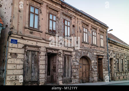 Ein Gebäude in Vukovar durchsetzt mit einschusslöchern und ein Denkmal für die Kroatischen Unabhängigkeitskrieg, Vukovar, Kroatien Stockfoto