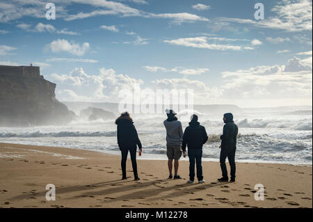 Eine Gruppe von vier Leute, die sich den großen Wellen am Praia do Norte, Nazare, Portugal. Stockfoto