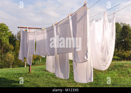 Frisches sauberes weißes Blatt trocknen auf der Wäscheleine im Freien Stockfoto