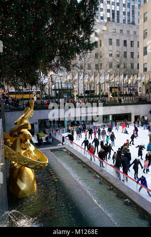 Die Eisbahn im Rockefeller Center mit dem goldenen Prometheus Skulptur im Vordergrund. Weihnachtszeit. Manhattan, New York City, USA. Stockfoto