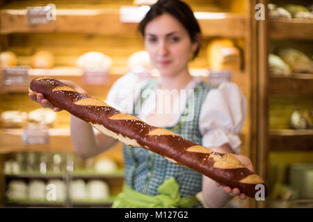 Junge Frau mit einem Baguette in eine Bäckerei Stockfoto