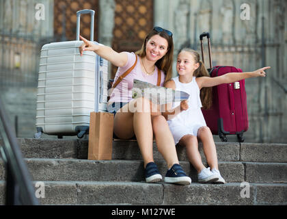 Portrait von reisenden Frau mit Mädchen sitzen auf alten Kathedrale Schritte suchen Karte Stockfoto