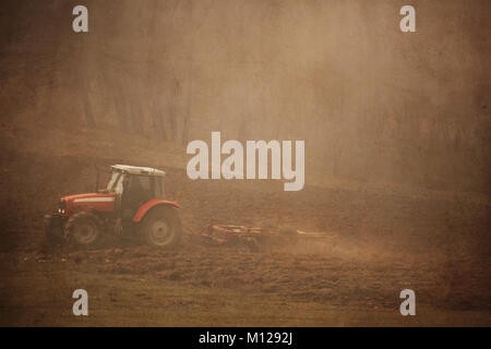 Fogy landwirtschaftlichen vintage Hintergrund mit Traktor im Feld in der Nähe von Forest Stockfoto