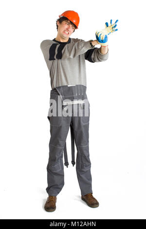 Ein junger Mann, der in der grauen Kleidung und orange-Helm auf einen Handschuh auf weißem Hintergrund isoliert. Stockfoto