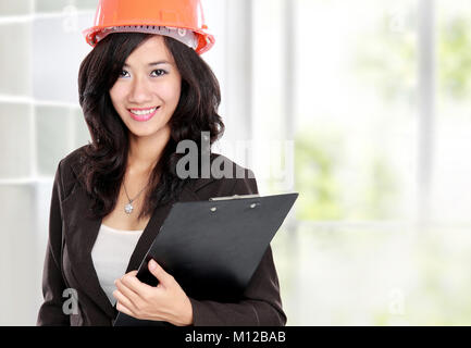 Selbstbewussten jungen Frau trägt orange Schutzhelm Helm Stockfoto