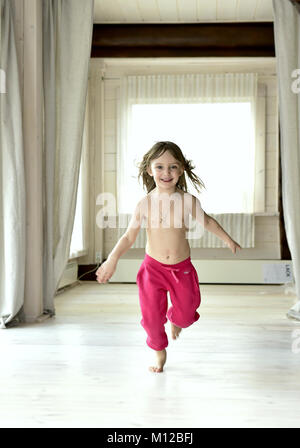 Glücklich lächelnde Mädchen das Tragen der roten Hosen auf weißen Boden Stockfoto