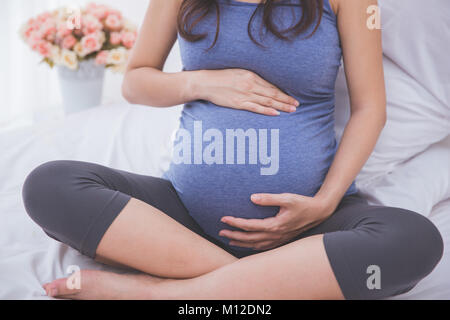 Eine Nahaufnahme portrait einer schwangeren Bauch gelehnt auf dem Bett Stockfoto