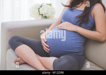 Nahaufnahme, Porträt einer schwangeren Bauch sitzen auf einer Couch Stockfoto