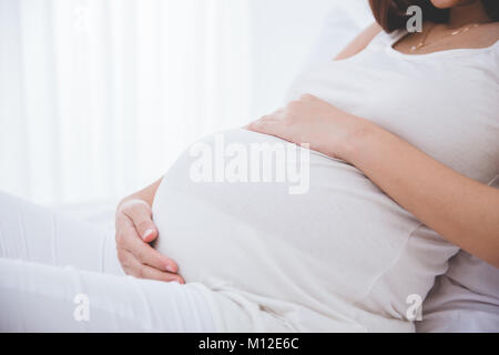 Eine Nahaufnahme portrait einer schwangeren Bauch gelehnt auf dem Bett Stockfoto