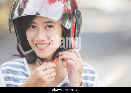 Glückliche Frau ihrem Motorrad Helm Befestigung in der Stadt. Stockfoto