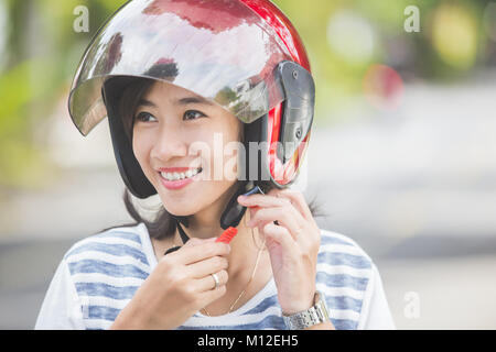 Glückliche Frau ihrem Motorrad Helm Befestigung in der Stadt. Stockfoto