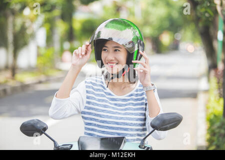 Glückliche Frau ihrem Motorrad Helm Befestigung in der Stadt. Stockfoto