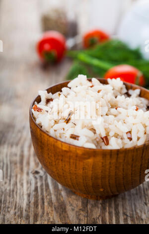 Gekochten Reis in eine hölzerne Schüssel auf dem Tisch. Lecker Abendessen. Stockfoto