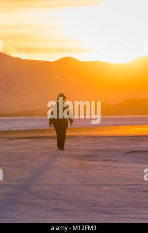 Frau zu Fuß in den Sonnenuntergang auf dem Bonneville Salt Flats, der BLM Land westlich der Great Salt Lake, Utah, USA Stockfoto