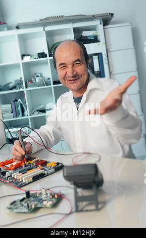 Ältere männliche tech Reparatur computer Motherboard lächeln in die Kamera Stockfoto