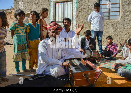 Musiker umgeben mit Kindern im Dorf Kanoi, Jaisalmer, Rajasthan, Indien Stockfoto
