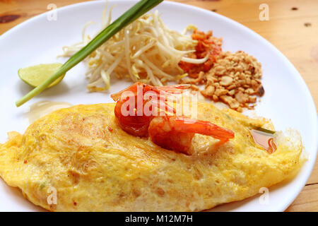 Hausgemachte Spiegelei gewickelt Pad Thai Nudeln mit Garnelen serviert auf weiße Platte Stockfoto