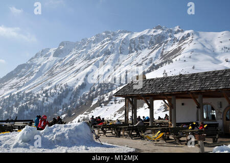 ARABBA, Italien - 7. MÄRZ 2011: Skifahrer und Snowboarder genießen einen Kaffee und ein Sonnenbad im Freien in einem Restaurant in den italienischen Dolomiten Stockfoto