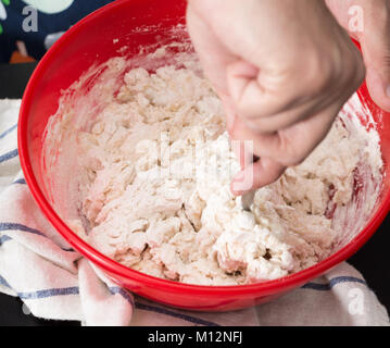 Männliche Hände machen/Mixing Teig in rot Schüssel, backen Vorbereitung Nahaufnahme. Stockfoto