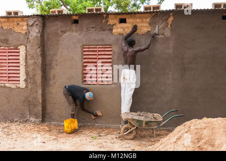 Zwei afrikanische Maurer arbeiten am Verputzen eines Brickwall, Ouagadougou, Burkina Faso. Stockfoto