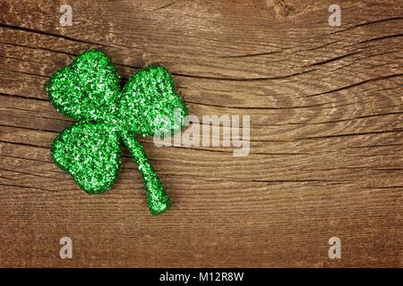 Einzelne St Patricks Day glittery Shamrock über ein altes rustikales Holz Hintergrund Stockfoto