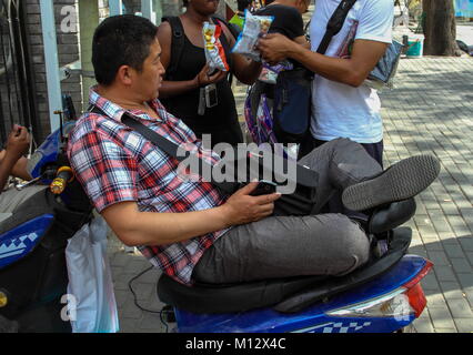 Xi'an, China - chinesische Büro sitzt auf seinem Roller auf der Straße auf seine Mittagspause, Bild im Querformat Stockfoto