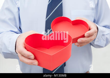 Mann, mit einem offenen roter Geschenkbox mit Herz Form in seinen Händen. Stockfoto