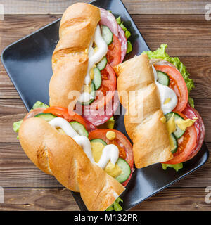 Fotografie von Sandwiches mit Wurst und Gemüse close-up auf hölzernen Tisch Stockfoto