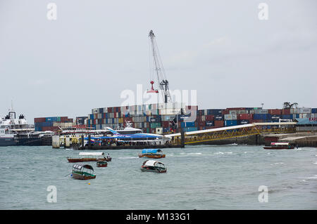 Container verladen auf einem Containerschiff im Hafen von Sansibar, Tansania, an einem sonnigen Tag mit dhaus im Vordergrund. Stockfoto