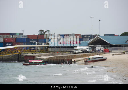 Container verladen auf einem Containerschiff im Hafen von Sansibar, Tansania, an einem sonnigen Tag mit dhaus im Vordergrund. Stockfoto