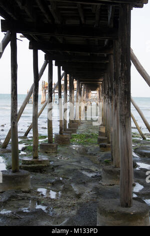 Ansicht unter einem Pier mit langen Holzstangen bei Ebbe über das türkisblaue Wasser des Indischen Ozean Meer in Nungwi, Sansibar, Tansania an einem sonnigen Tag Stockfoto