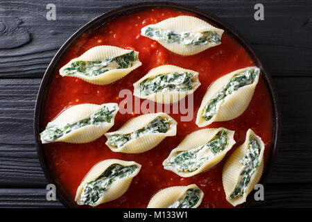 Köstliche conchiglioni Pasta gefüllt mit Spinat und Ricotta mit Tomatensauce close-up auf einem Teller. horizontal oben Ansicht von oben Stockfoto