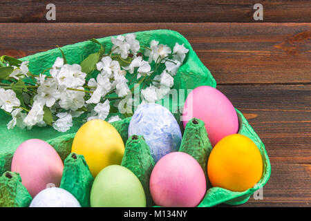 Bunte Ostereier in einer grünen Fach auf eine braune Holztisch Stockfoto