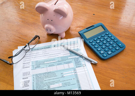 IRS Tax Form mit Sparschwein, Taschenrechner, Stift und Gläser Stockfoto