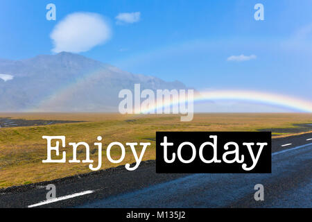 Inspirational motivation Angebot mit Phrase genießen heute, isländische Landschaft unter einem blauen hellen Himmel mit Regenbogen Stockfoto