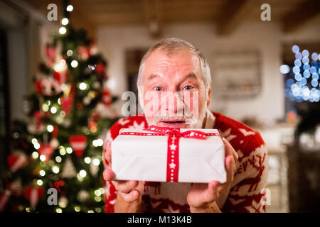 Älterer Mann vor Weihnachten mit einem Geschenk. Stockfoto