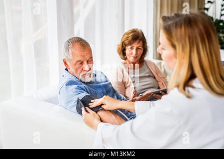 Ärztin Kontrolle Blutdruck von älteren Menschen. Stockfoto