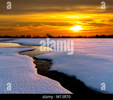 Sonnenuntergang über Bach über Winter Wiese Stockfoto