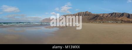 Spanien, Kanarische Inseln, Lanzarote, Caleta de Famara, am Famara Strand Surfer vor dem Risco de Famara Felsen Stockfoto