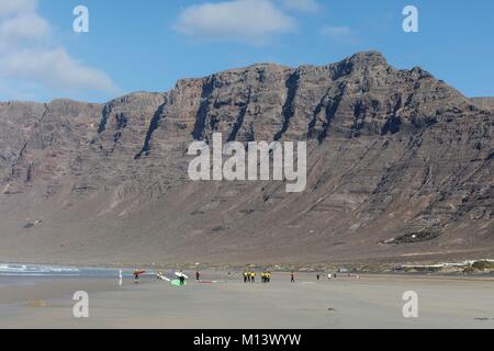 Spanien, Kanarische Inseln, Lanzarote, Caleta de Famara, am Famara Strand Surfer vor dem Risco de Famara Felsen Stockfoto