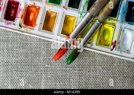 Hintergrund des Pinsels abgedeckt in der Farbe liegen auf dem Satz von hellen Wasserfarben auf gewebe Sackleinen Stockfoto