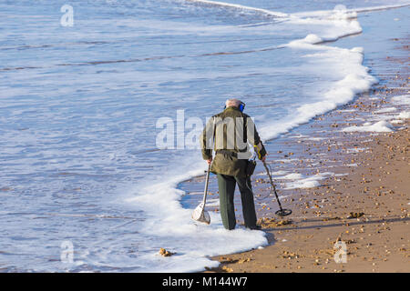 Beach Comber mit Metalldetektor auf der Suche nach Schatz bei der Strand von Bournemouth Bournemouth, Dorset UK im Januar Stockfoto