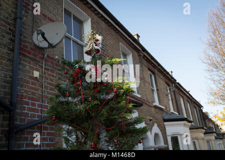 Ein Baum mit Weihnachtsschmuck gekleidet sitzt außerhalb eines viktorianischen Reihenhaus in Herne Hill, SE24, am 18. Dezember 2017 in London, England. Stockfoto