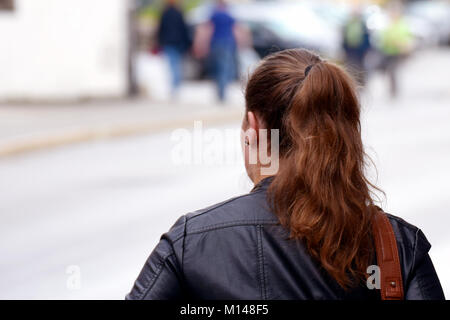 Junge Frau zu Fuß auf die Straße. Andere Menschen auf verschwommenen Hintergrund. Nahaufnahme Rückansicht Bild mit Platz für Text. Stockfoto