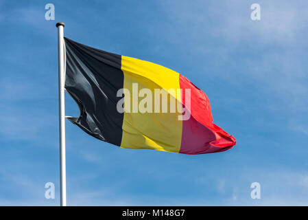 Nahaufnahme des einzigen belgischen Flagge wackeln im Wind vor blauem Himmel Stockfoto